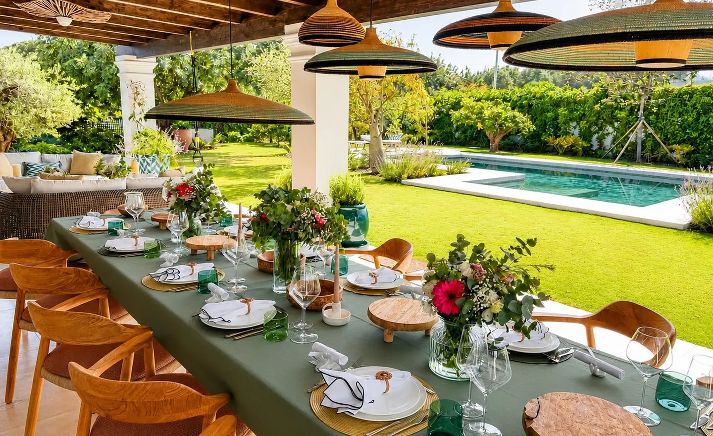 A long green table prepared beside a pool for a private celebration